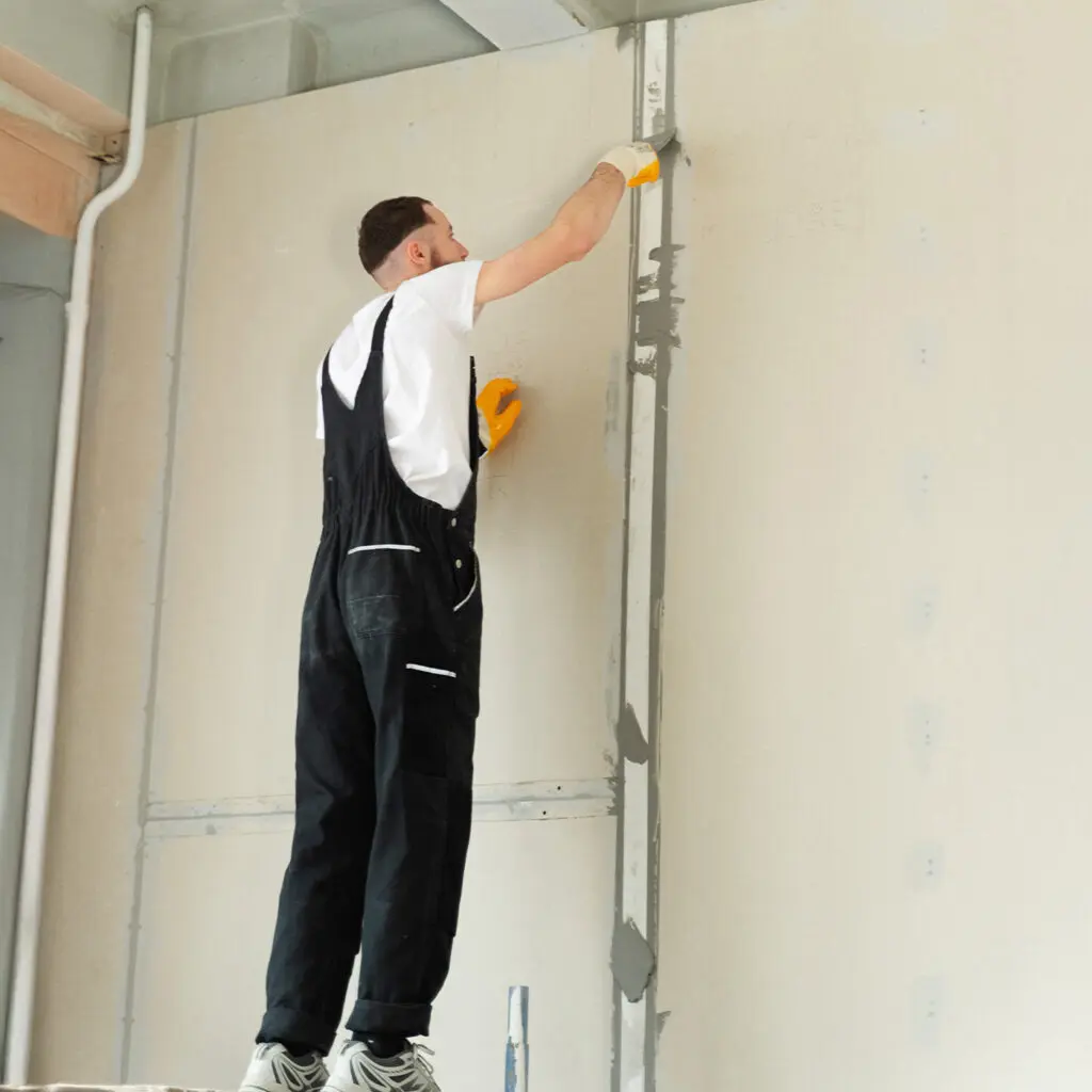 Traditional drywall partition wall under construction using metal stud framing and plasterboard